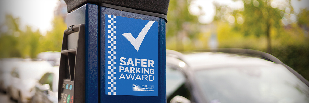 A payment machine in a car park displaying the Safer Parking Award poster