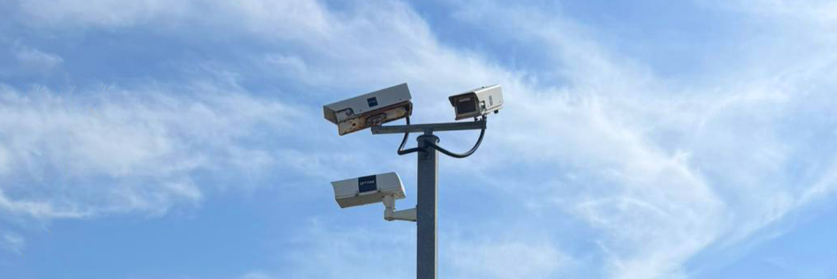 Three CCTV cameras pointing in various directions to monitor a car park's activity