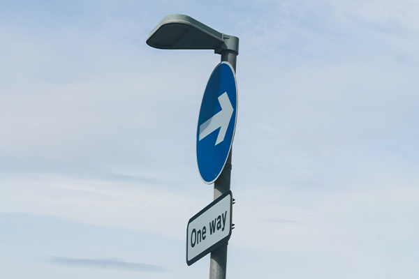 A one way sign and directional arrow